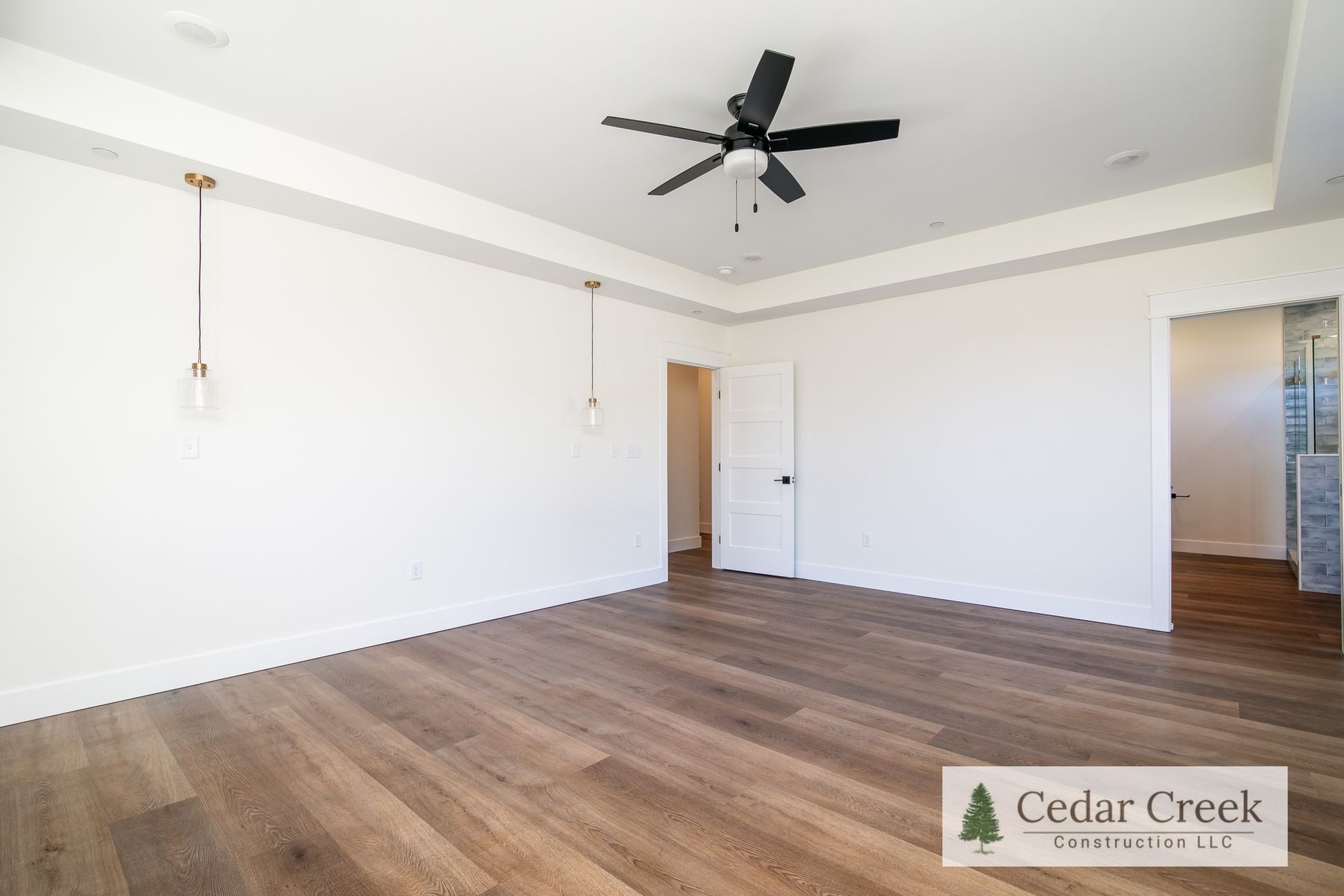 A large empty room with hardwood floors and a ceiling fan