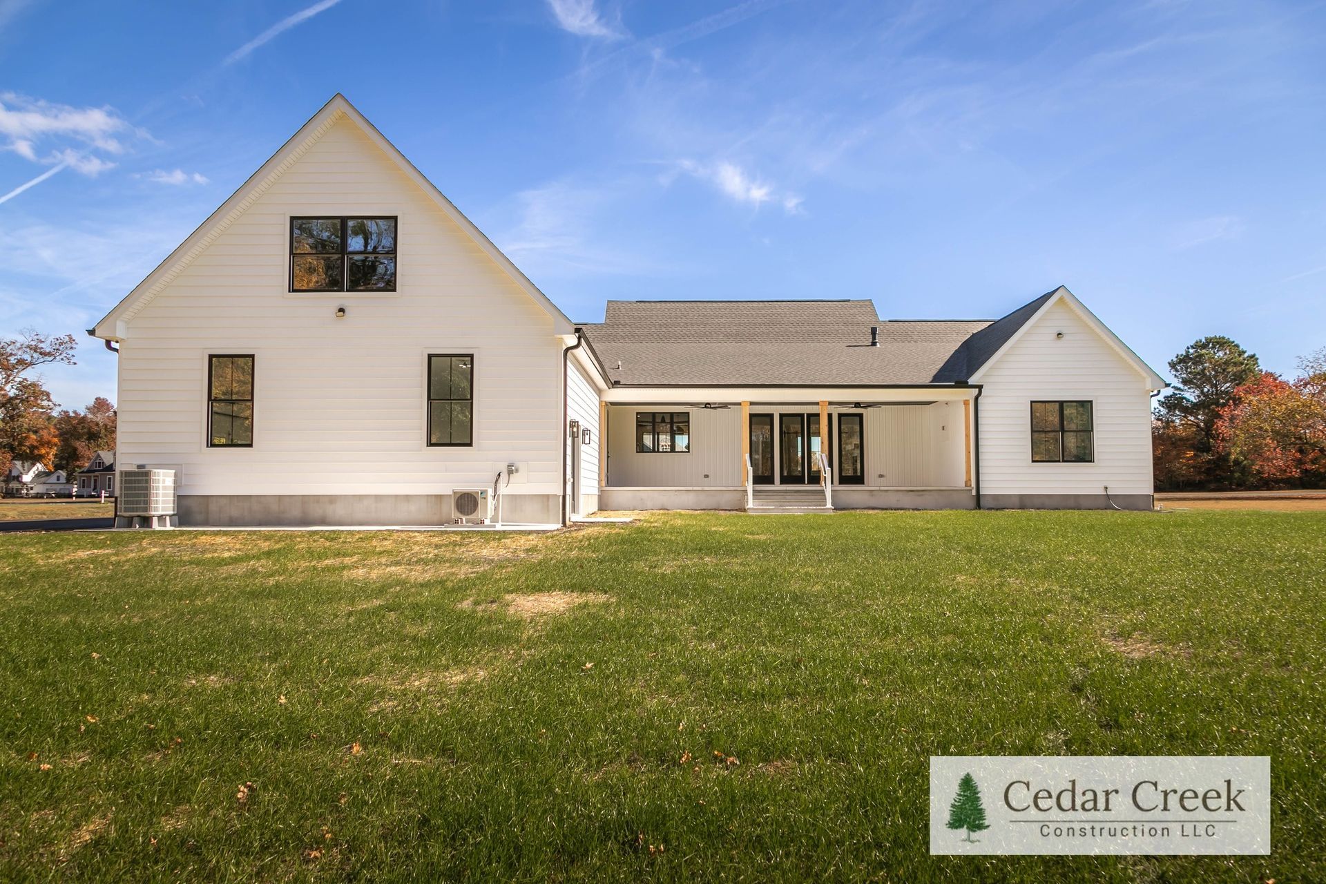 A large white house is sitting on top of a lush green field