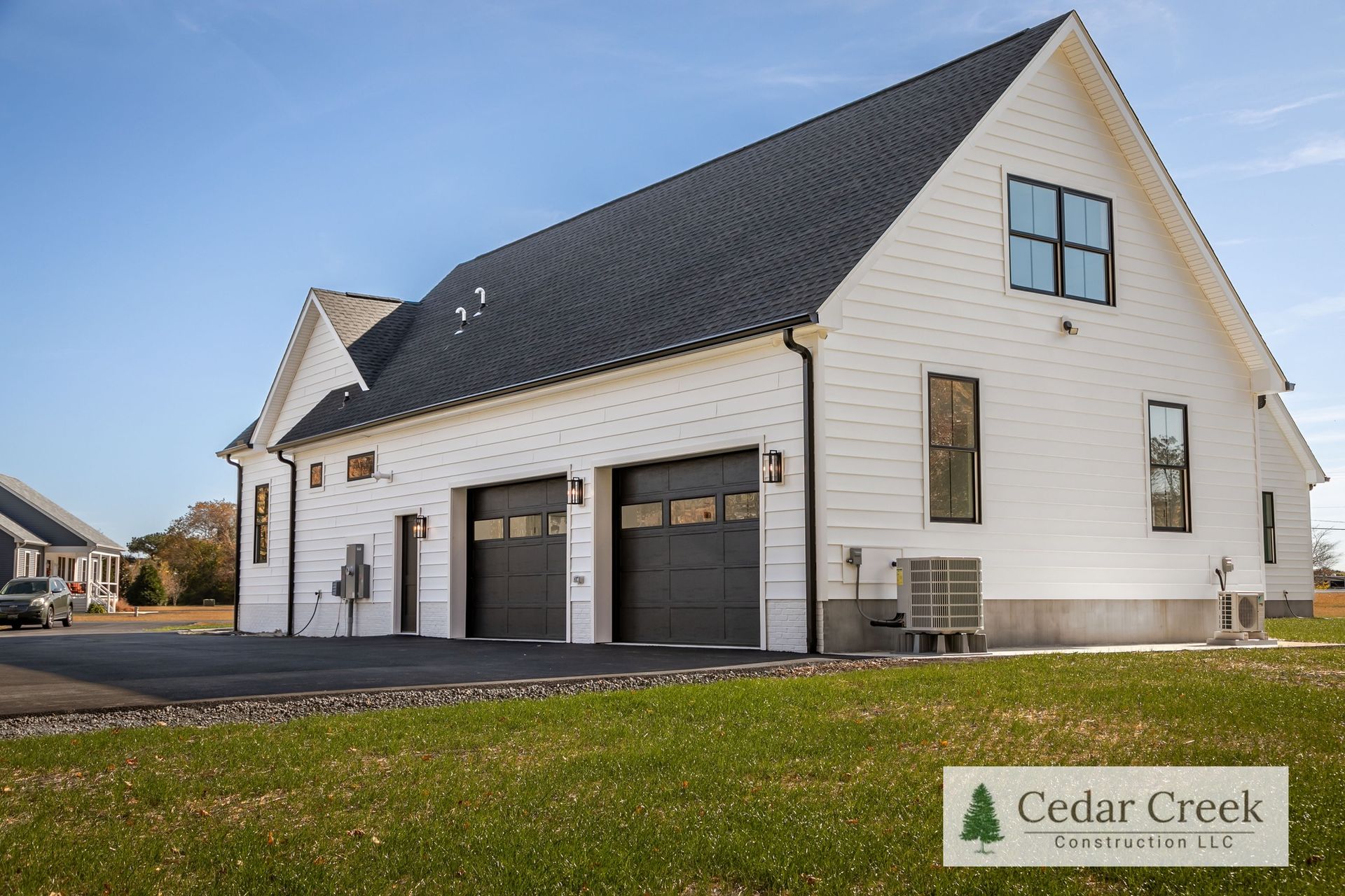 A white house with black garage doors and a black roof