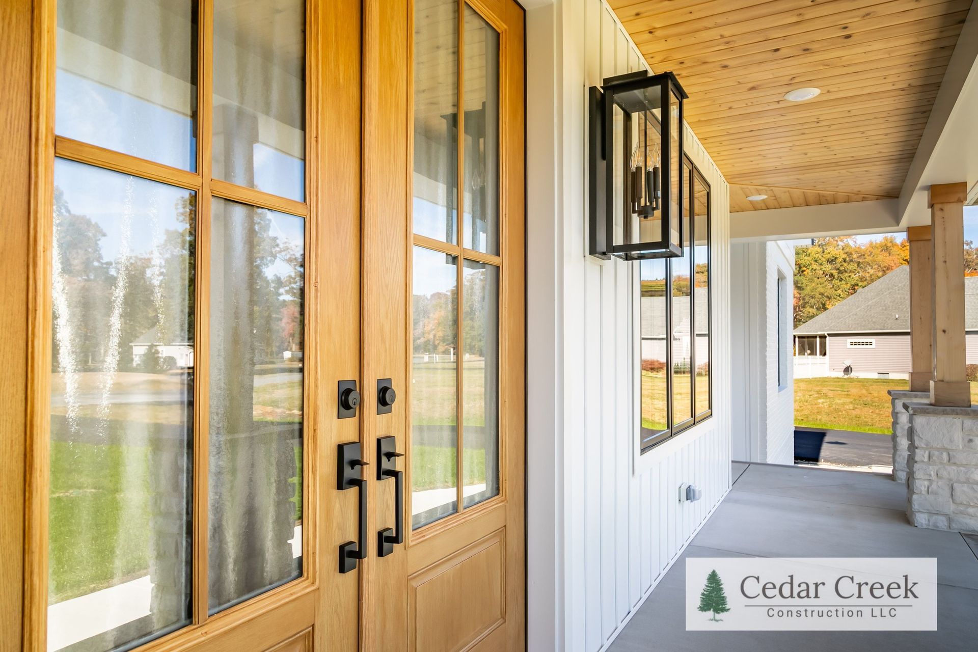 The front door of a house with a porch and a lantern on the wall