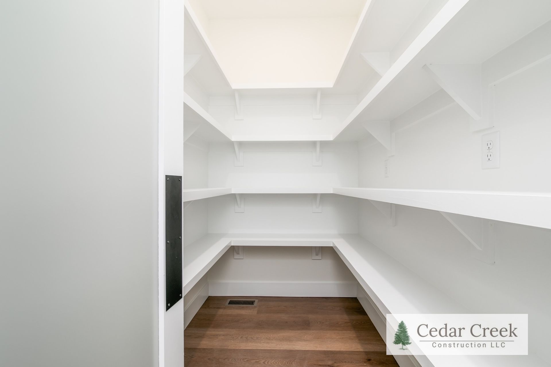 A pantry with white shelves and wooden floors in a house