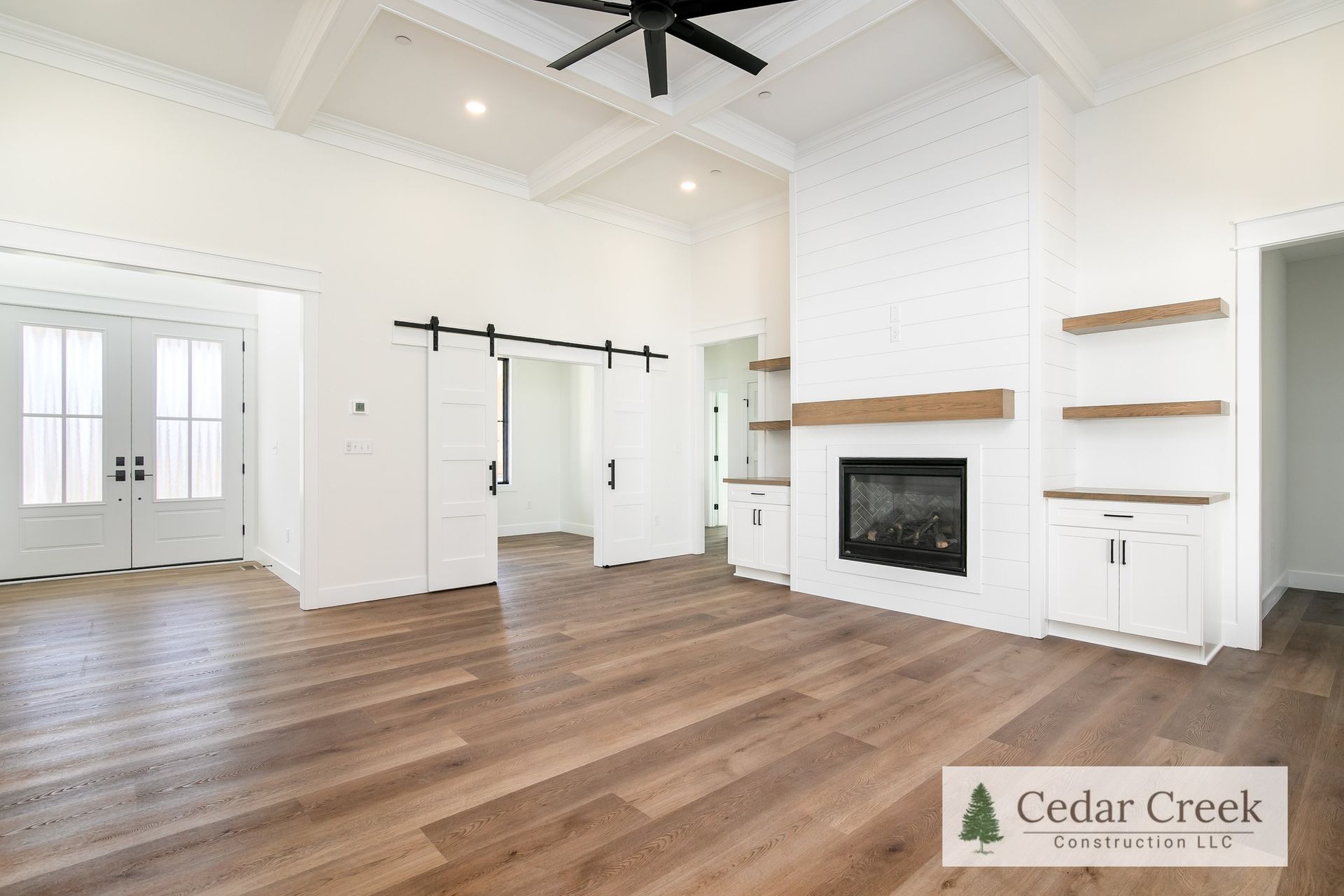 A living room with hardwood floors, a fireplace and a ceiling fan