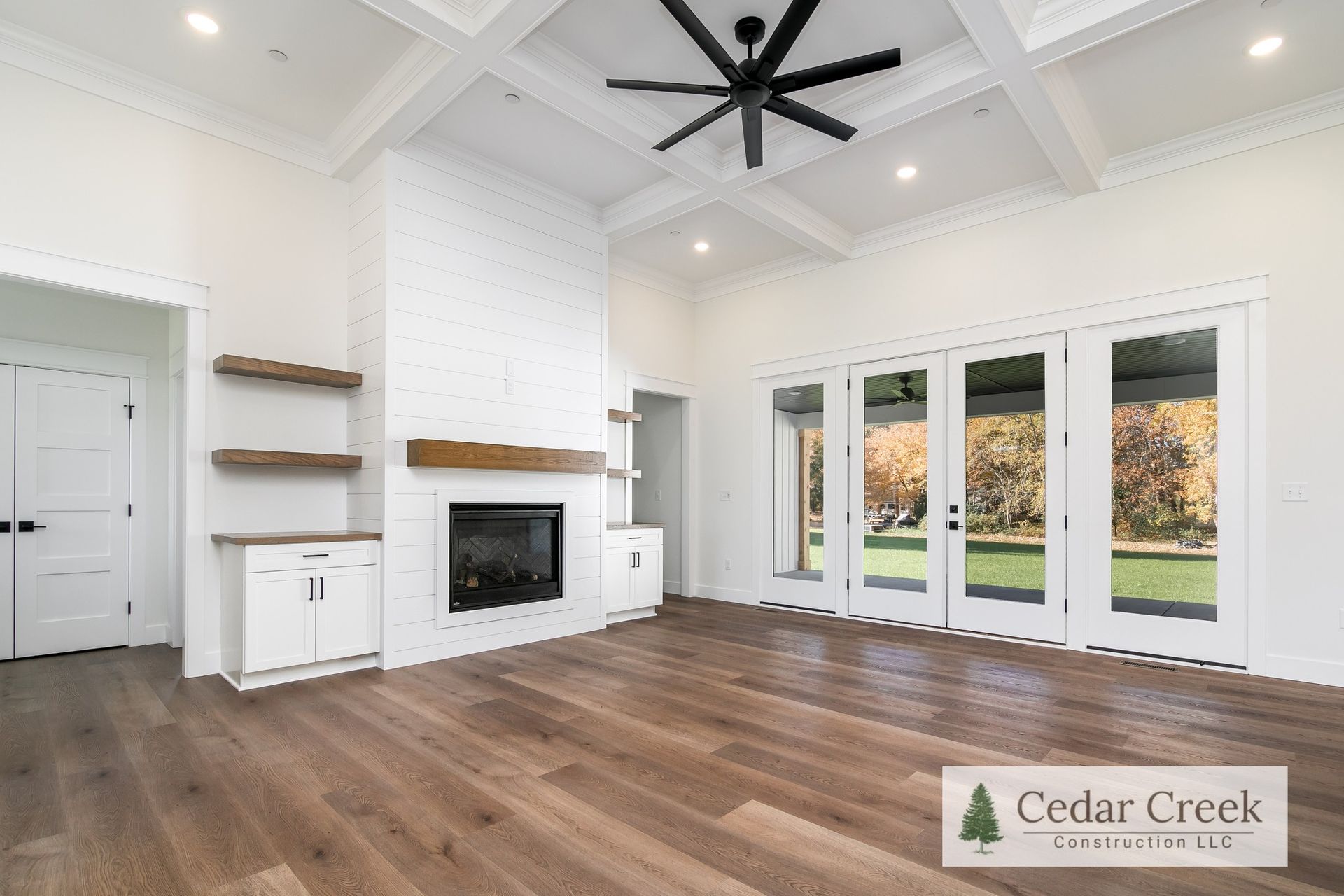 A living room with hardwood floors, a fireplace and a ceiling fan