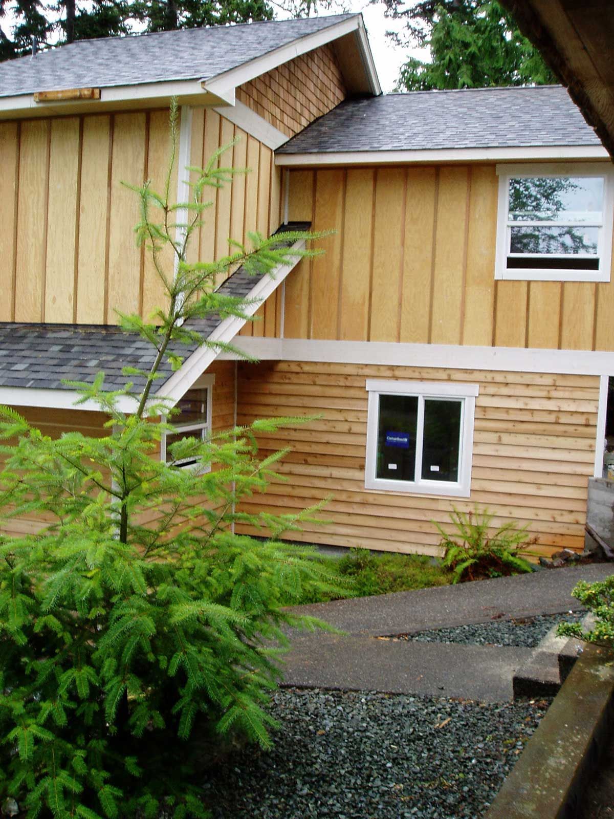 A wooden house with a gray roof and white windows