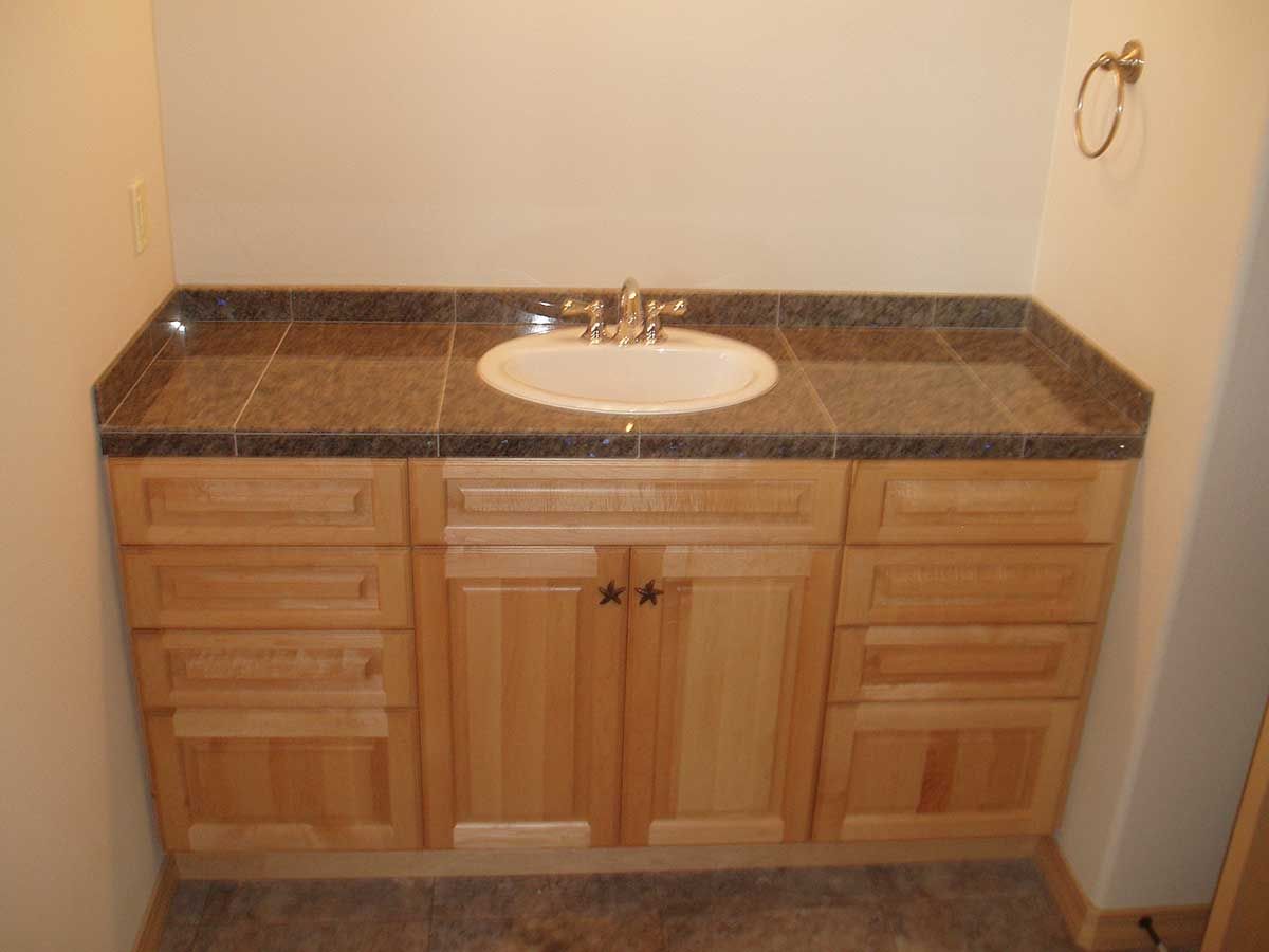 A bathroom sink with wooden cabinets and granite counter top