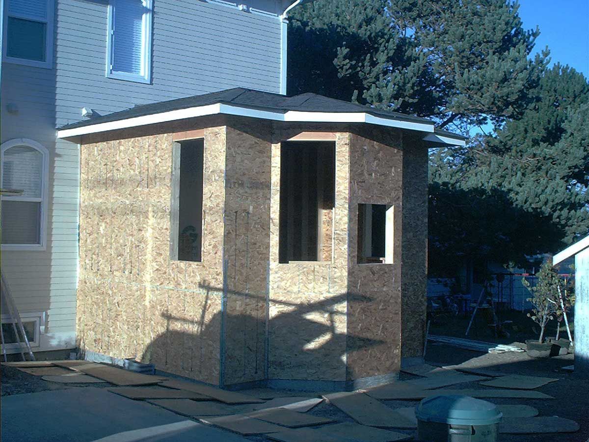A shed is being built in the backyard of a house.