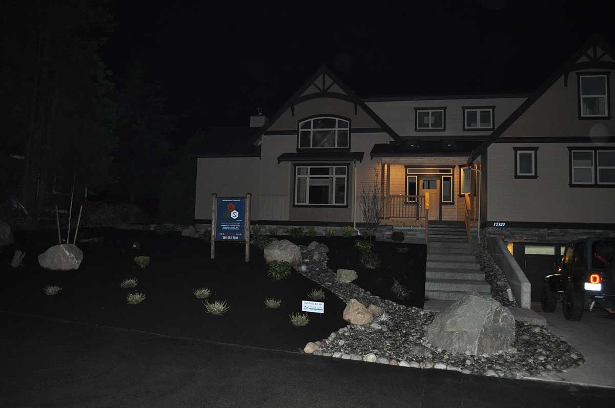 A large house is lit up at night with a mailbox in front of it.