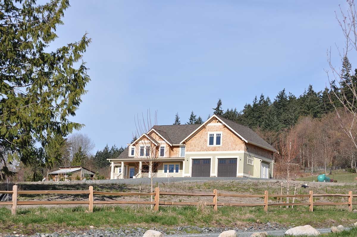 A house is being built in a field with a wooden fence in front of it.