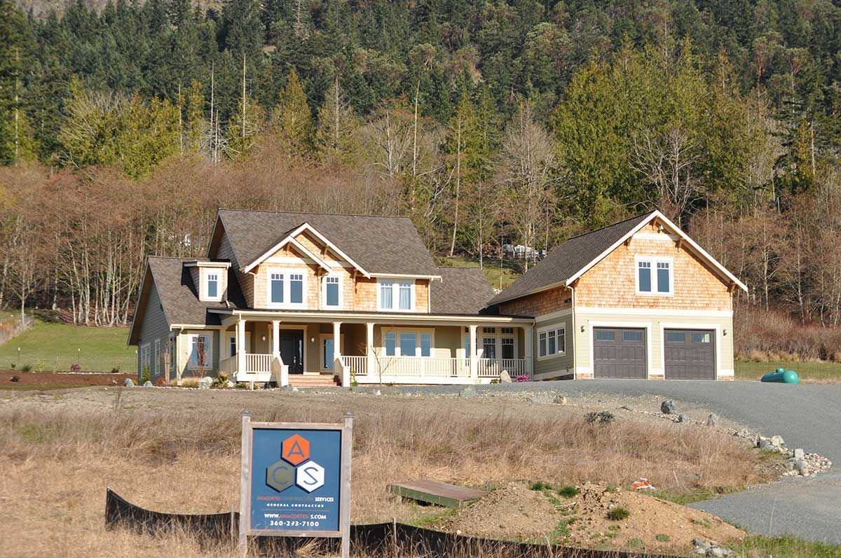 A large house is sitting in the middle of a field surrounded by trees.