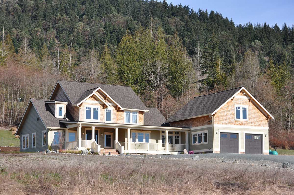 A large house sits in the middle of a field surrounded by trees