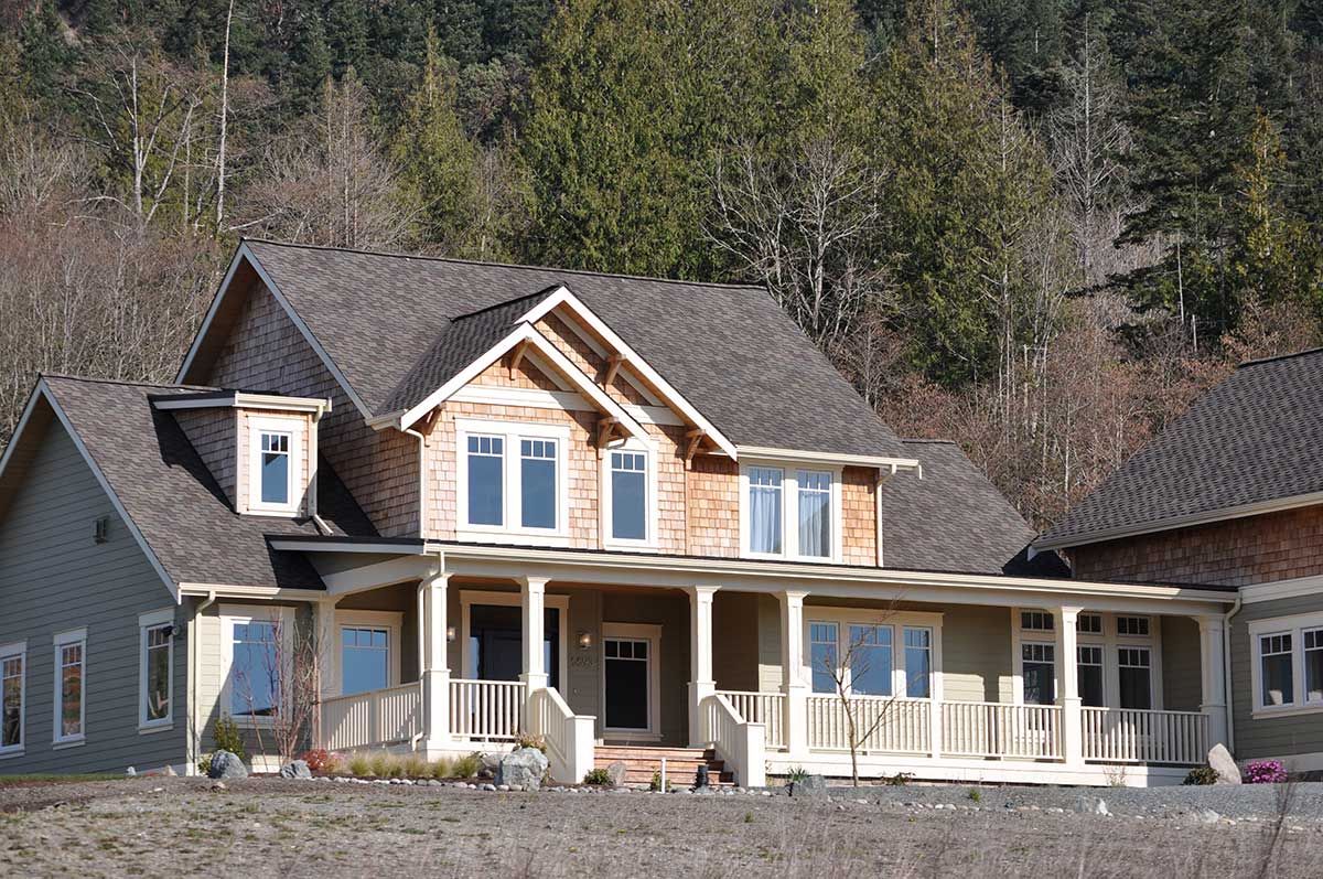 A large house with a large porch is surrounded by trees