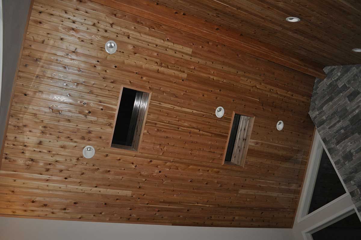 A wooden ceiling with holes in it and a fireplace in the background.