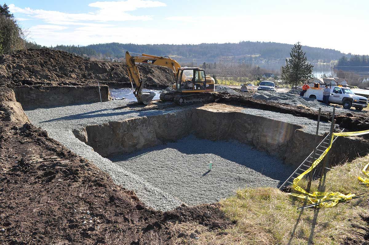 A yellow excavator is digging a large hole in the ground.