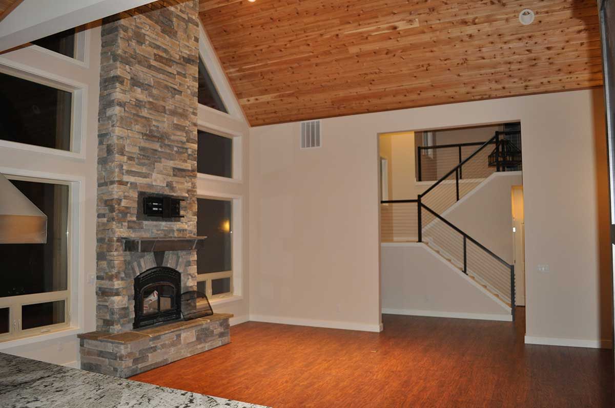 An empty living room with a stone fireplace and stairs