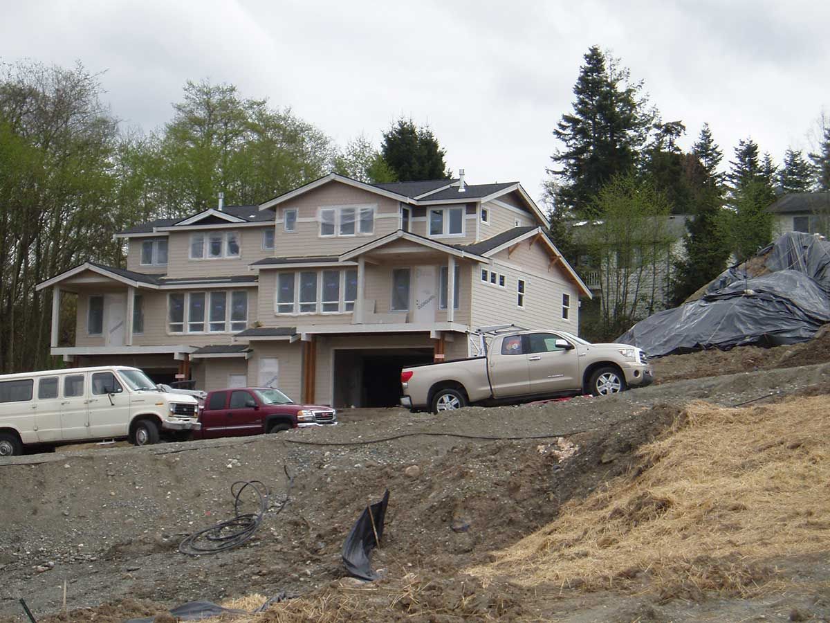 Several trucks are parked in front of a house under construction