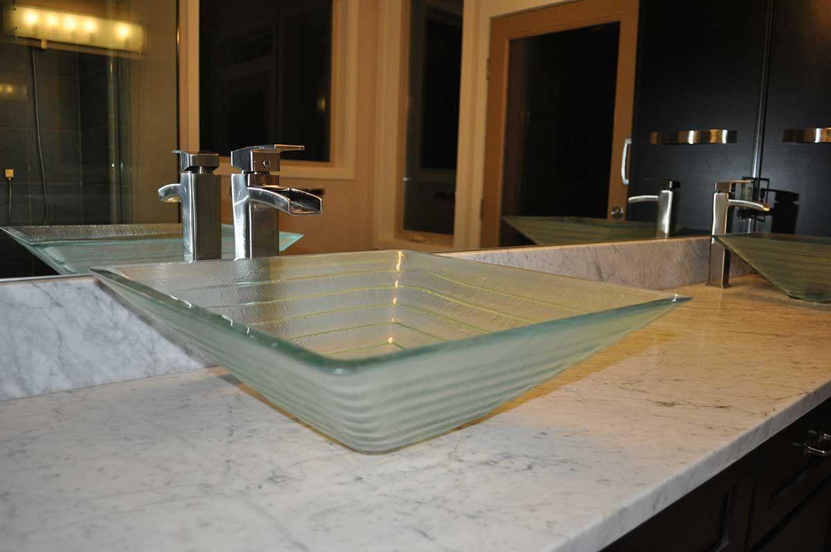A bathroom sink with two faucets and a mirror.