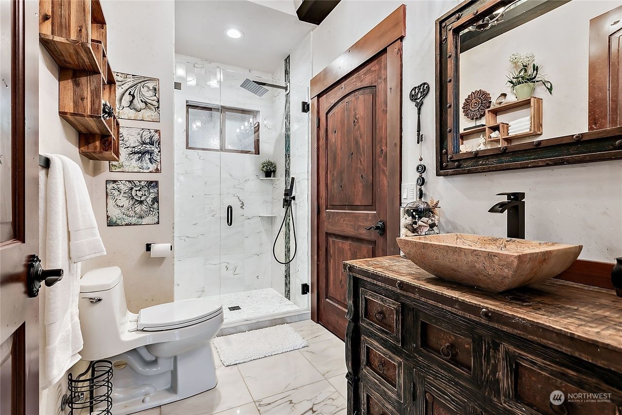 A bathroom with a toilet, sink, mirror and shower.