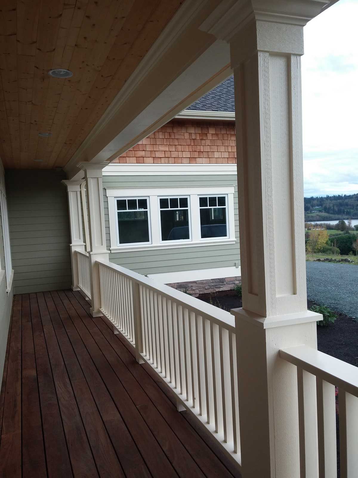 A porch with a white railing and a house in the background