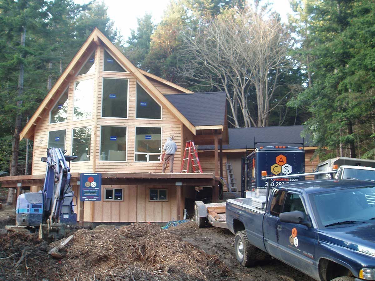 A blue truck is parked in front of a house under construction