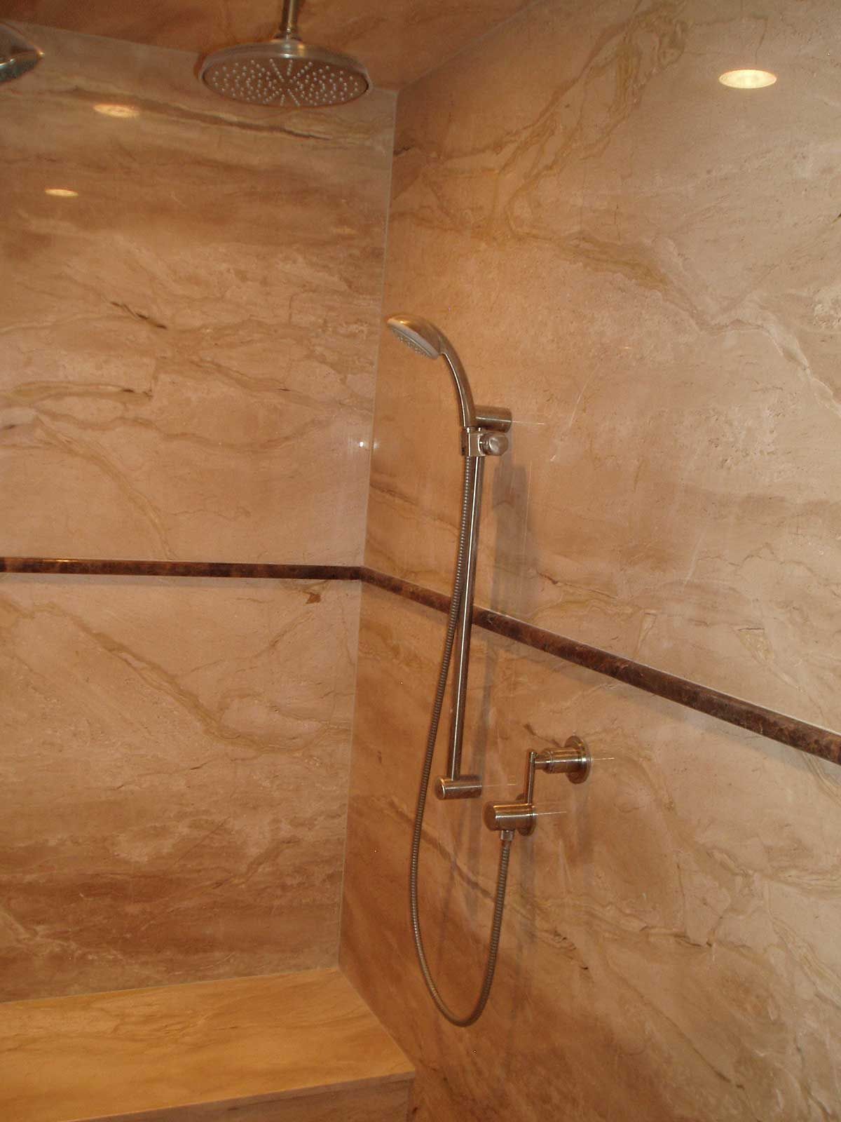 A shower with a marble wall and a shower head