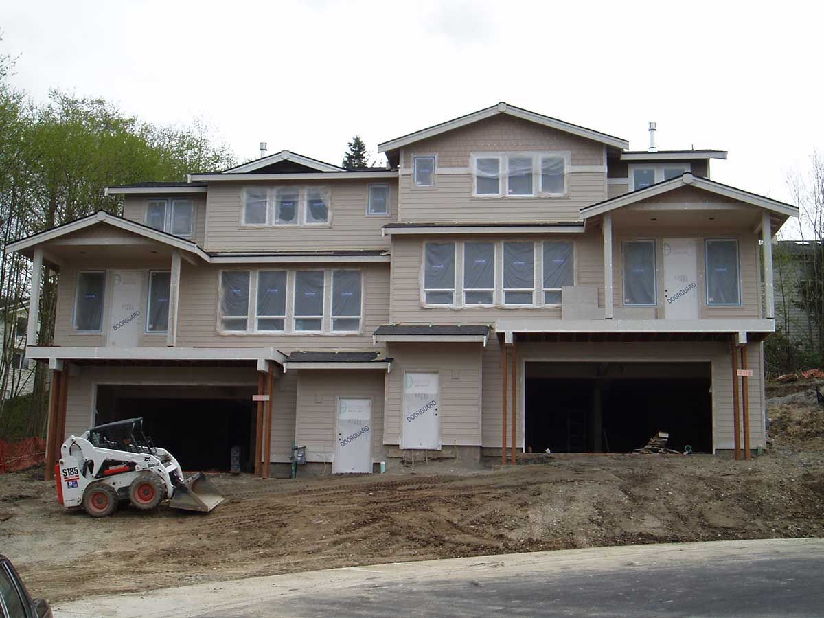 A bobcat is parked in front of a house under construction