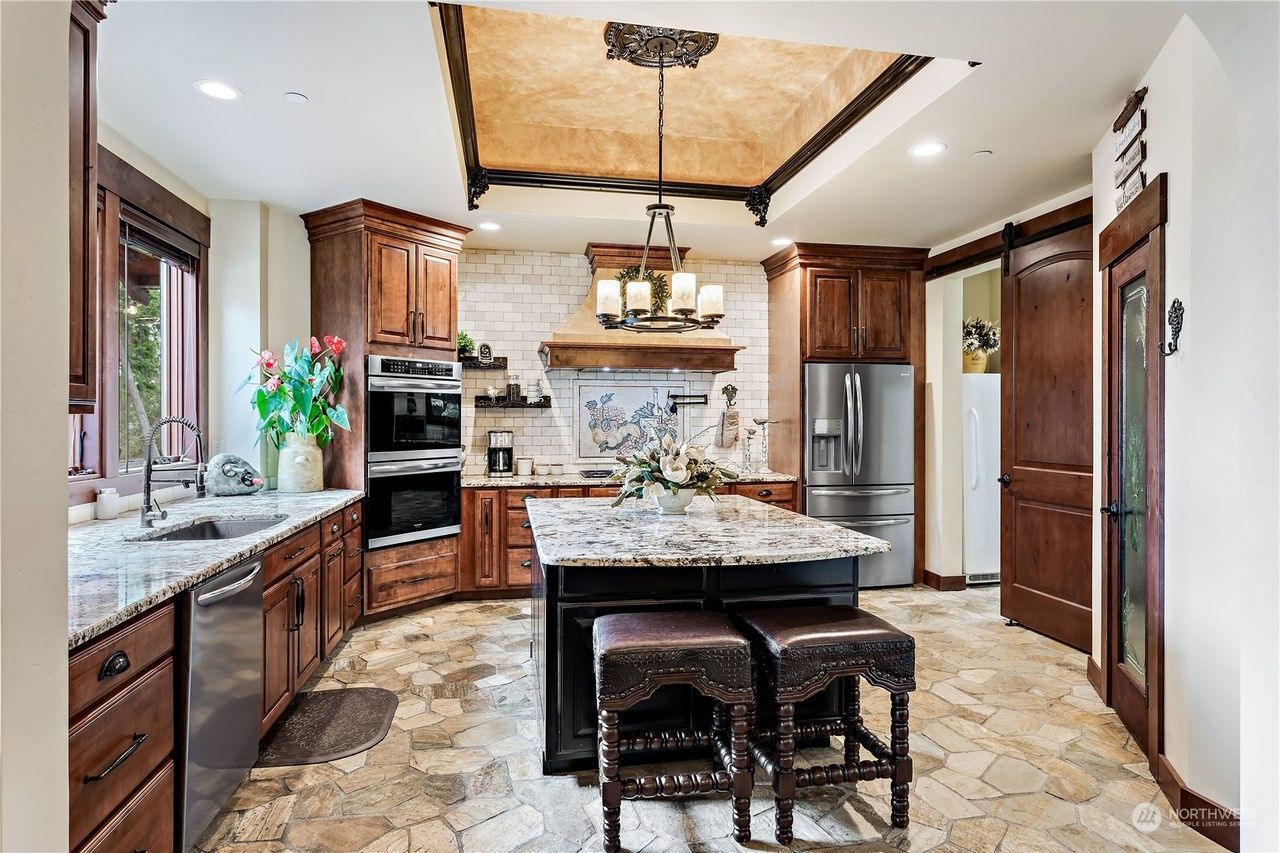 A kitchen with wooden cabinets, granite counter tops, stainless steel appliances, and a large island.