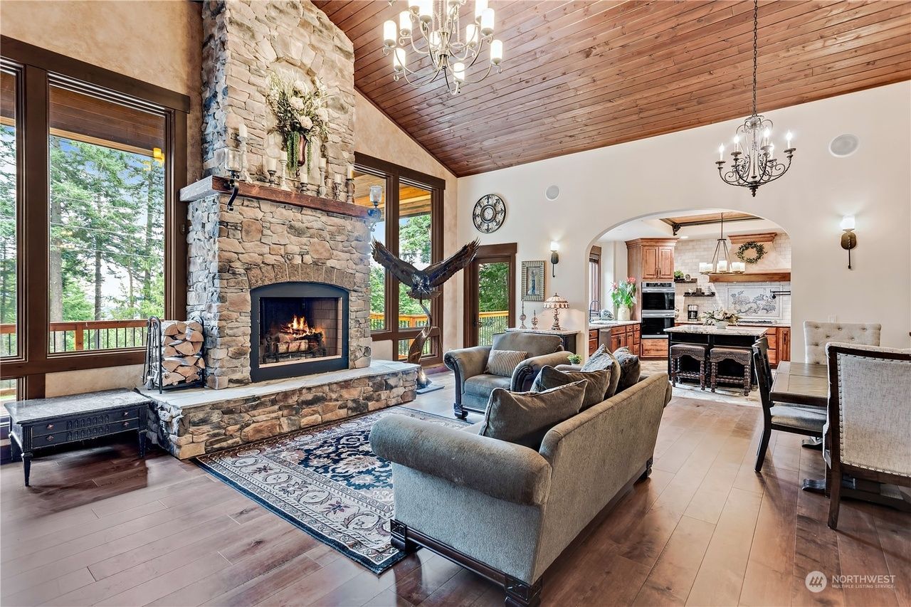 A living room with a fireplace, couch, chairs, and a chandelier.