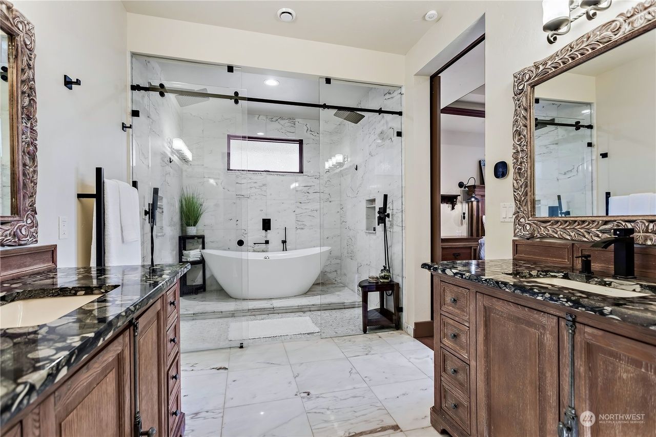 A bathroom with two sinks, a tub, and a mirror.