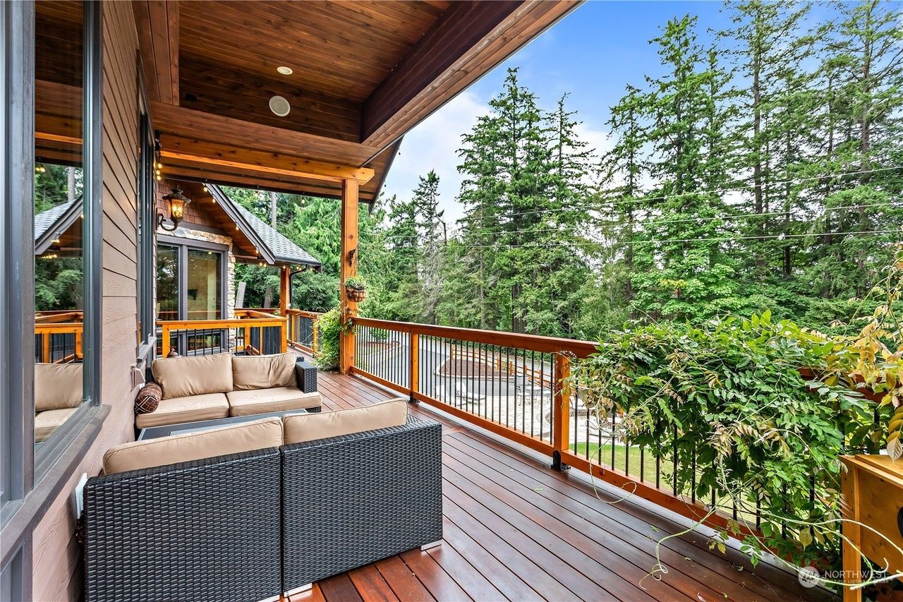 A large wooden deck with a couch and chairs on it.