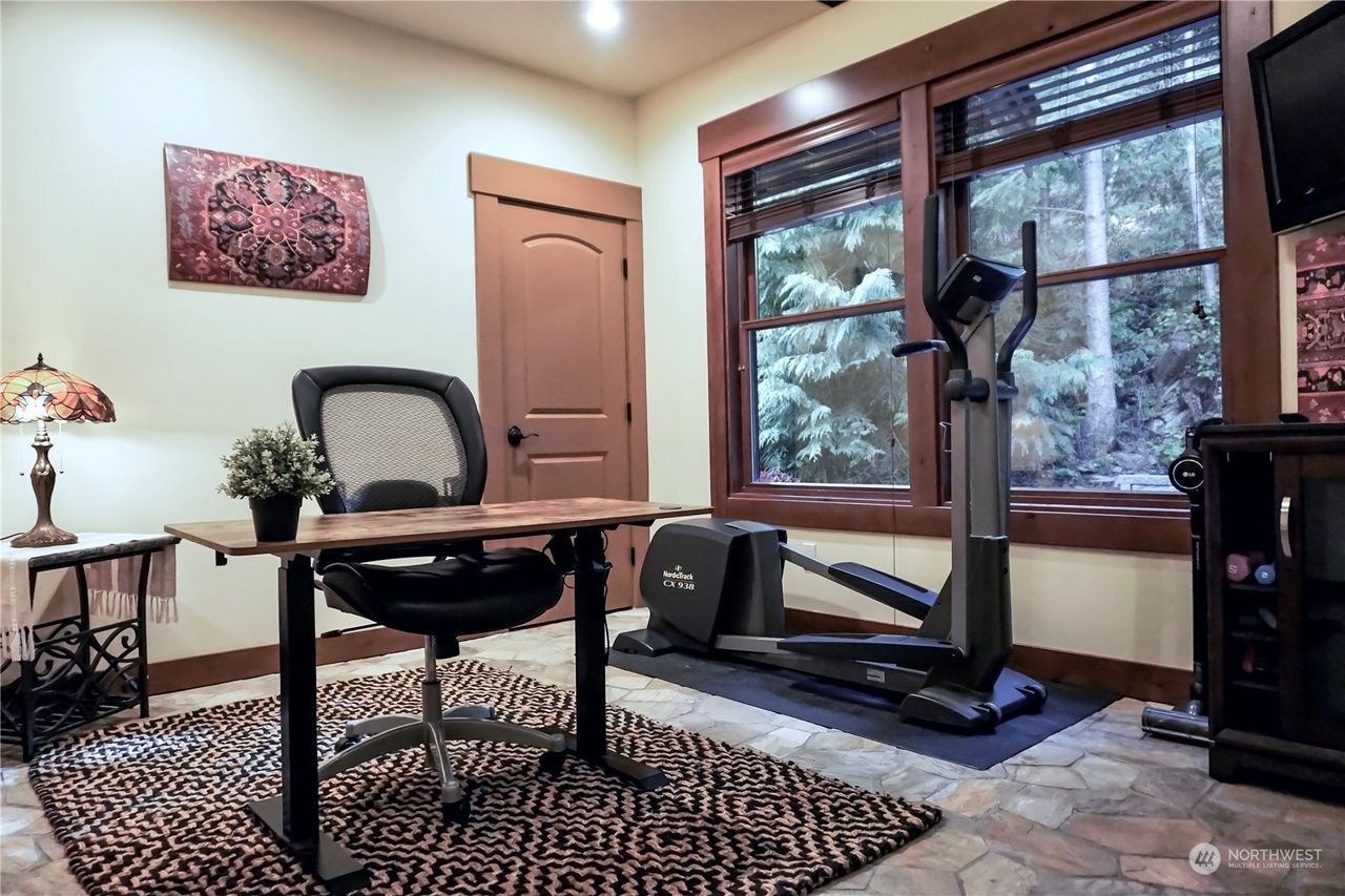 A home office with a desk, chair, and exercise bike.