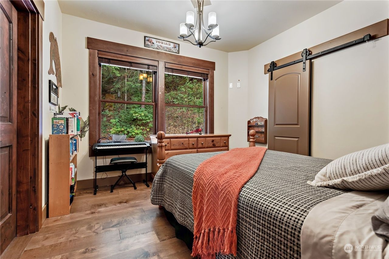 A bedroom with a bed, desk, and sliding barn doors.