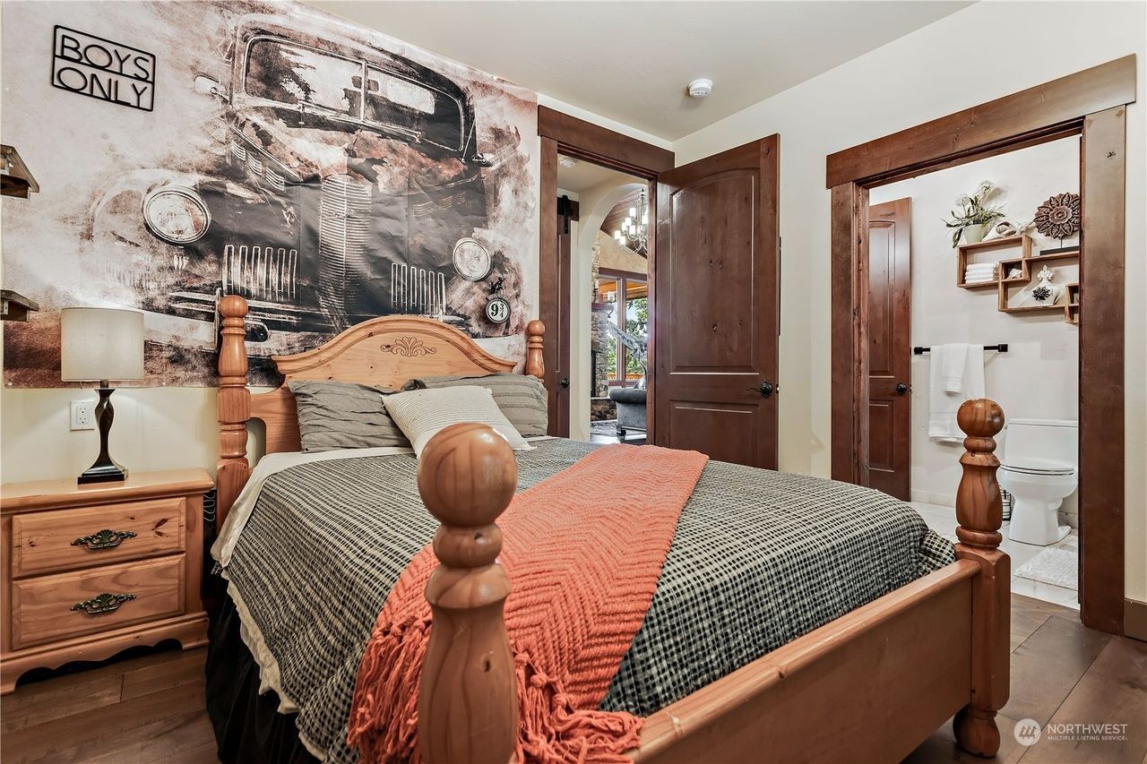 A bedroom with a bed, nightstand, lamp, and a mural on the wall.