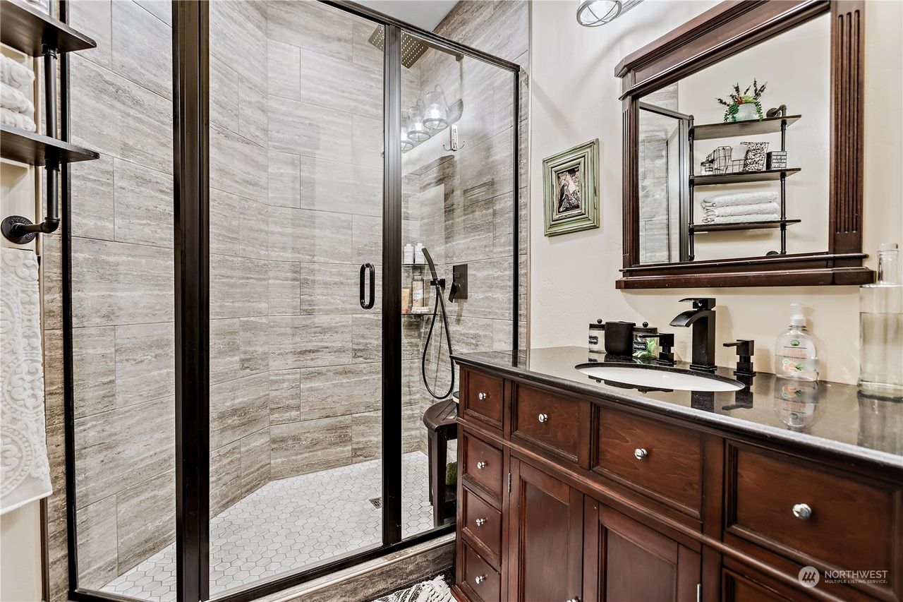 A bathroom with a walk-in shower, sink, and mirror.