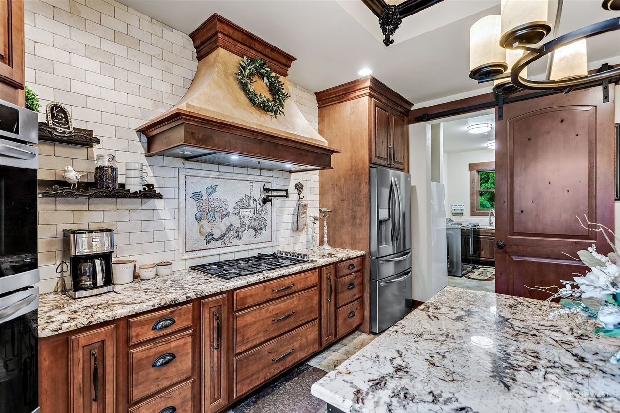 A kitchen with wooden cabinets, granite countertops, stainless steel appliances, and a large island.