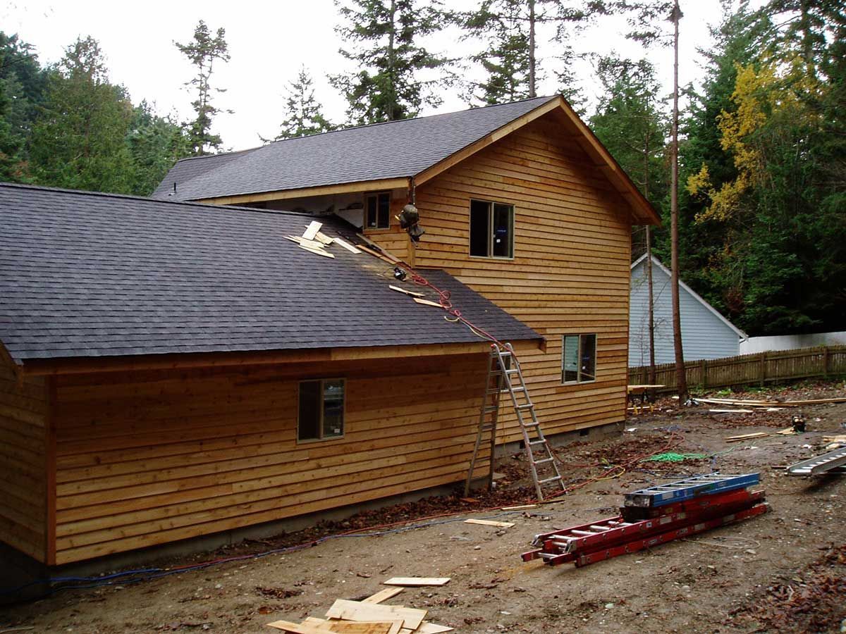 A wooden house with a black roof is being built