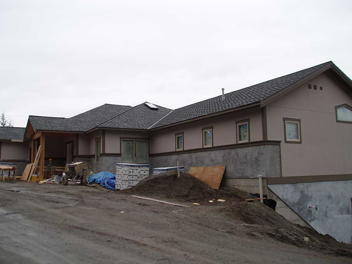 A large house with a gray roof is under construction