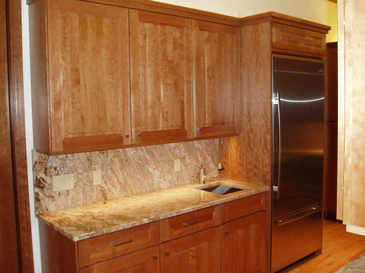 A kitchen with wooden cabinets and a stainless steel refrigerator