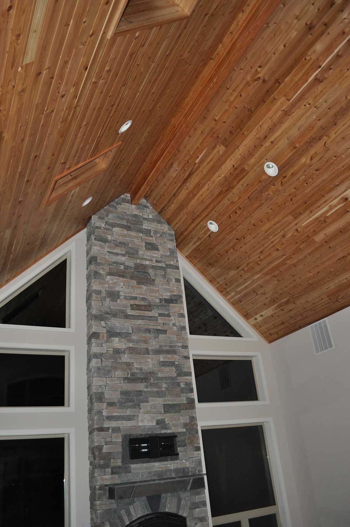 A living room with a wooden ceiling and a stone fireplace.