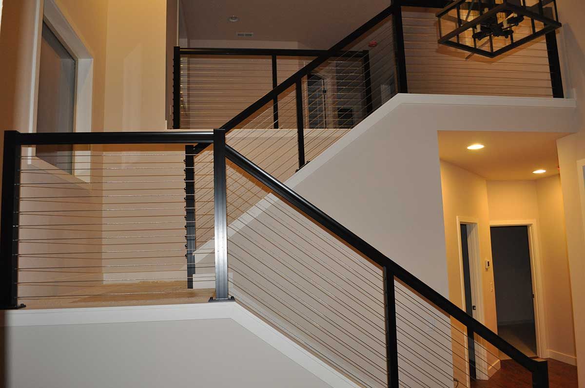 A staircase with a black railing and a white carpet