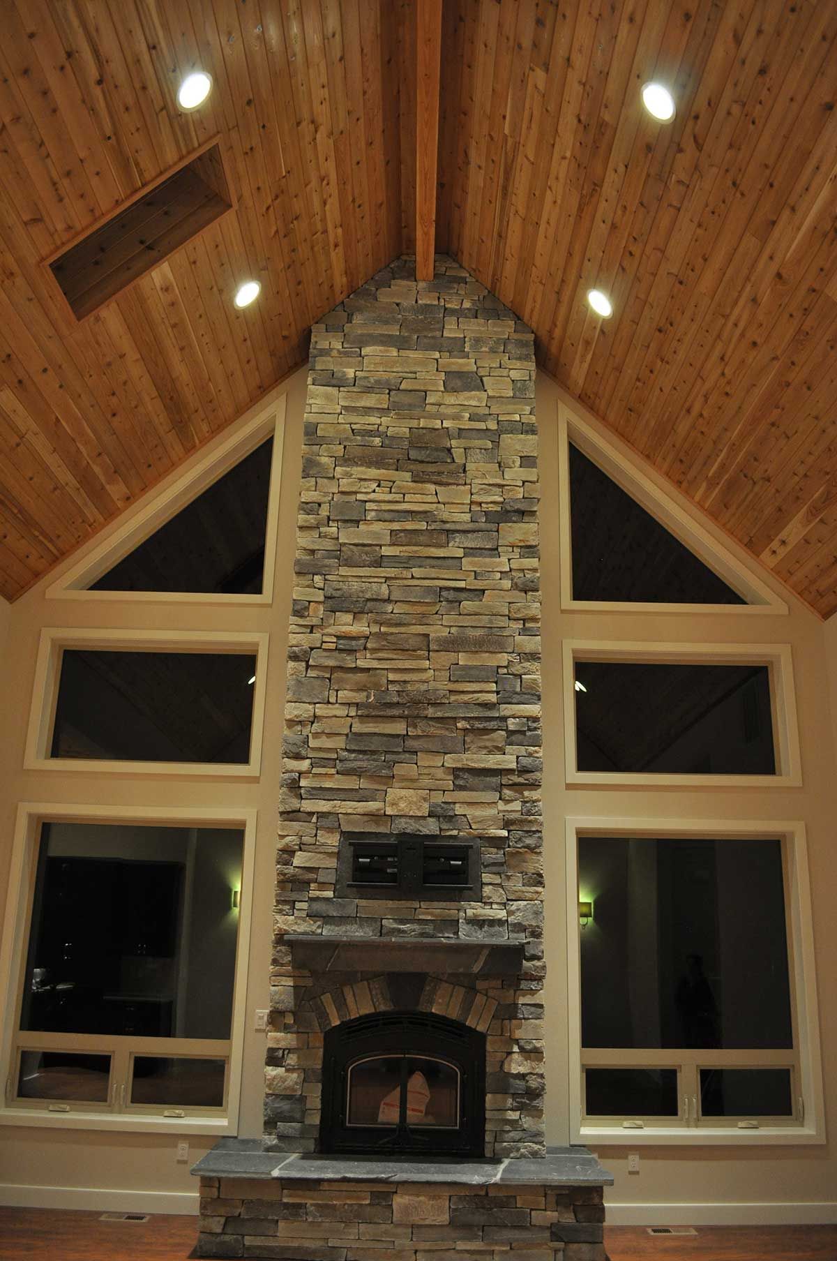 A large stone fireplace in a living room with a vaulted ceiling.