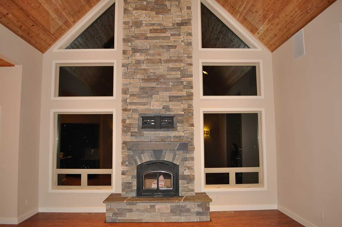 A living room with a stone fireplace and lots of windows