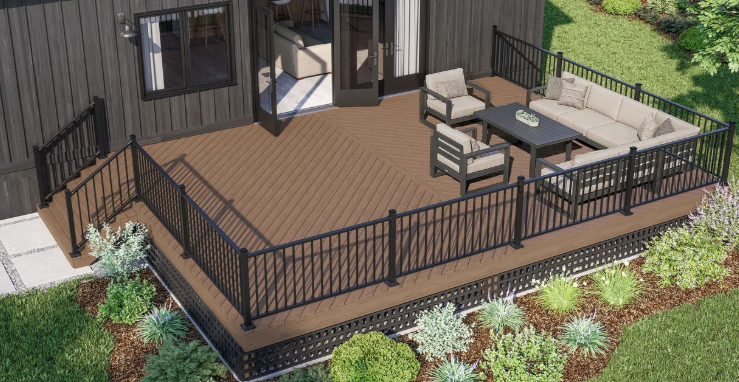Wooden deck with black railing, patio furniture, and a sliding door beside a landscaped yard