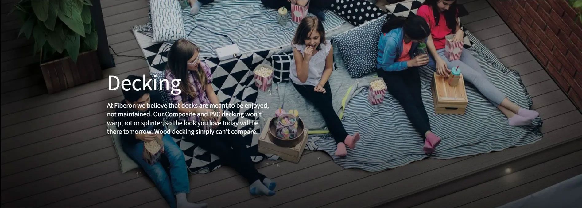 A group of people sit on blankets on a deck, eating snacks, with the text