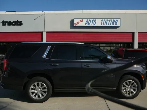 Black SUV parked in front of an auto testing shop with red-and-white storefront signs