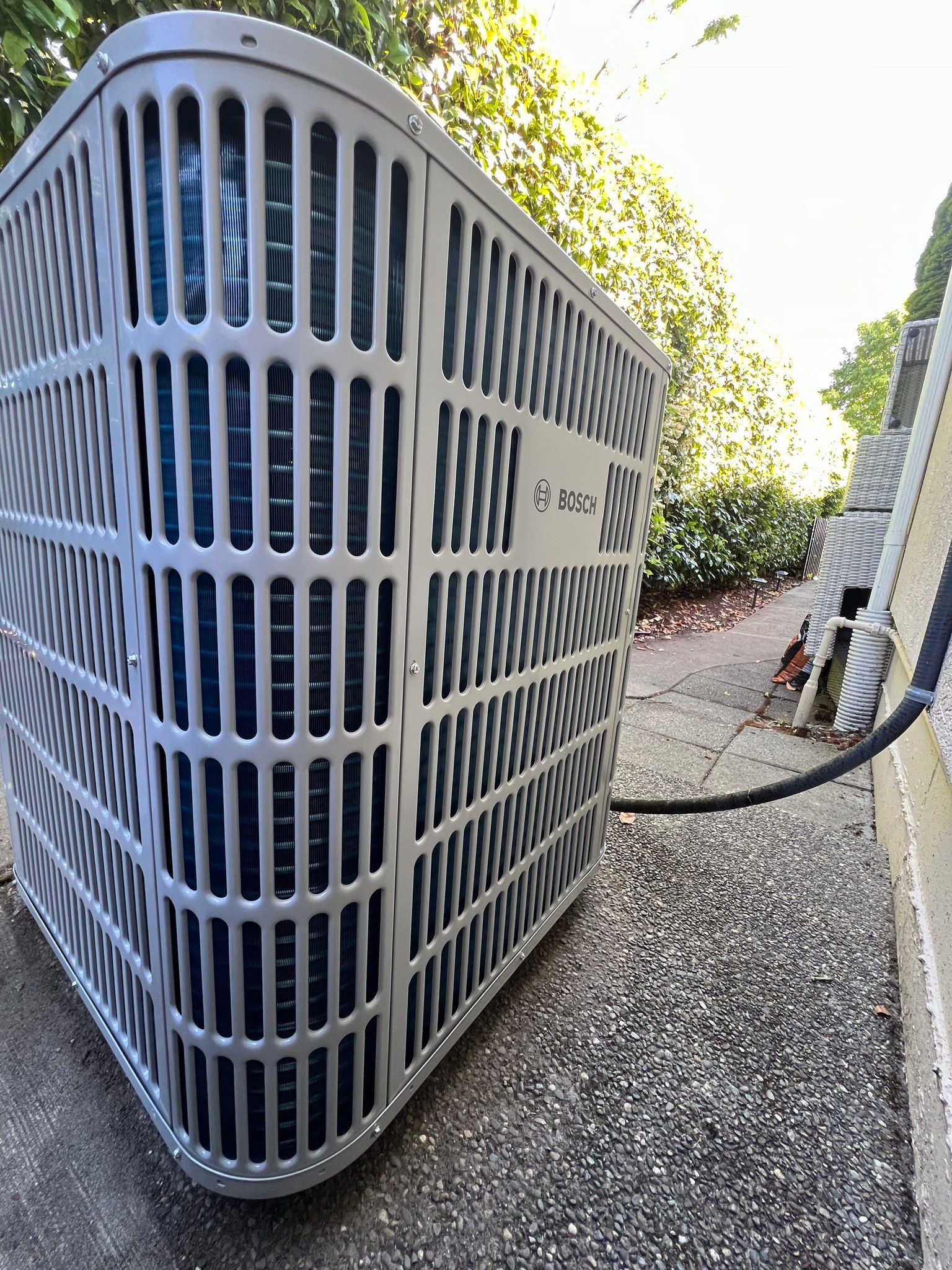 Gray air conditioning unit on a gravel surface next to a building.