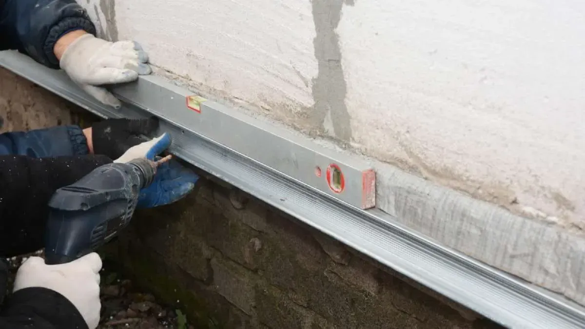 Workers using a level to install a metal track on a wall.