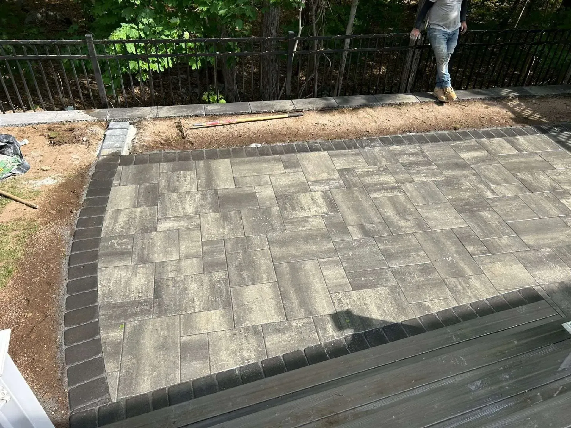 Newly constructed patio with brick pavers and a person standing nearby.