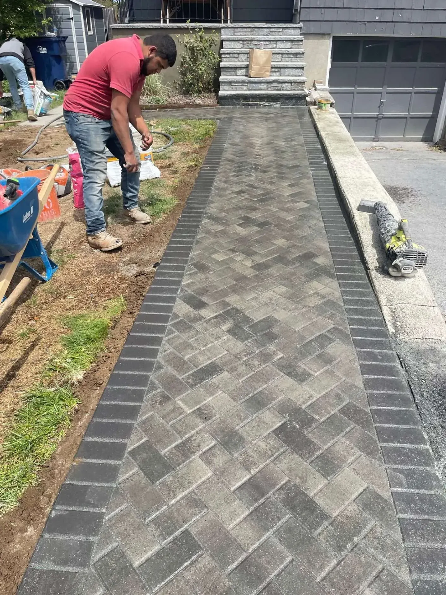 Man laying herringbone brick walkway with dark border.