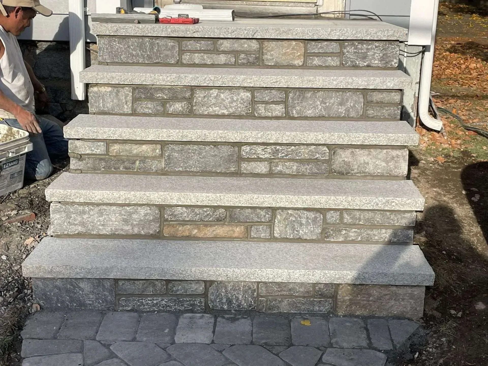 Stone steps leading to a building's entrance; a person is working on the steps.