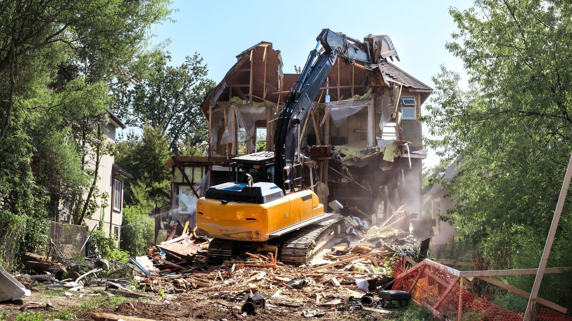 A large house is being demolished by a bulldozer.